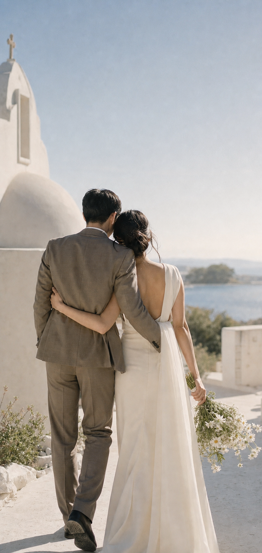 Pareja de novios caminando frente a una capilla costera